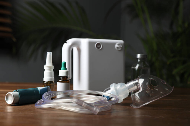 Modern nebulizer with face mask and medications on wooden table indoors. Inhalation equipment - Foto, afbeelding