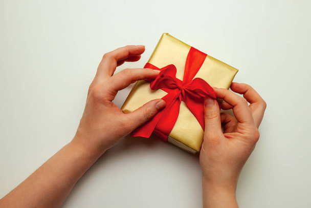 休日の贈り物。白い背景に赤い弓で包み込む金のギフトの箱。メリークリスマス、ハッピーニューイヤー、バレンタインデーの挨拶 - 写真・画像