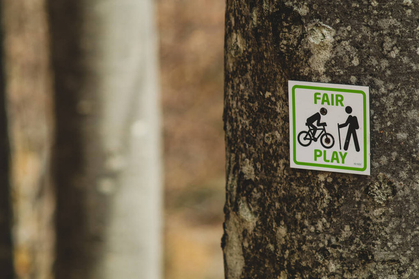 Uma placa de sinalização em uma árvore que ilustra o fair play ou o uso justo de trilhas entre ciclistas de montanha e caminhantes ou montanhistas. - Foto, Imagem