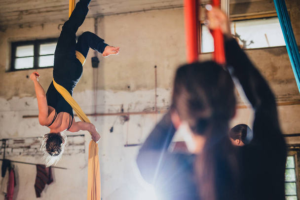 Uma mulher dançarina de ginástica aérea em corda de seda atuando em um ambiente industrial de uma oficina ou armazém abandonado. - Foto, Imagem