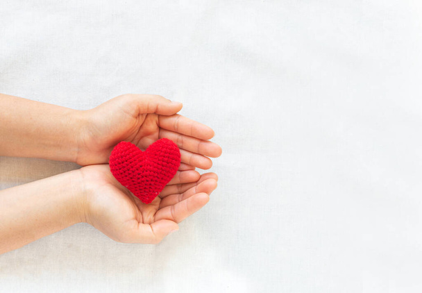 Χέρια κρατώντας κόκκινη καρδιά σε λευκό απομονωμένο φόντο, αντίγραφο χώρου, έννοια της αγάπης, ελπίδα, υγειονομική περίθαλψη, δωρεά οργάνων, ασφάλιση και ΕΚΕ, Παγκόσμια ημέρα καρδιάς, Εθνική Ημέρα Δωρητή Οργάνων, Παγκόσμια ημέρα πνευματικής υγείας. - Φωτογραφία, εικόνα