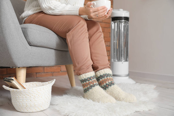 Jeune femme en vêtements chauds et une tasse de thé à la maison. Concept de saison de chauffage - Photo, image