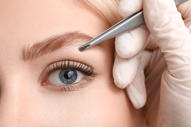 Young woman undergoing eyebrow correction procedure, closeup - Фото, изображение