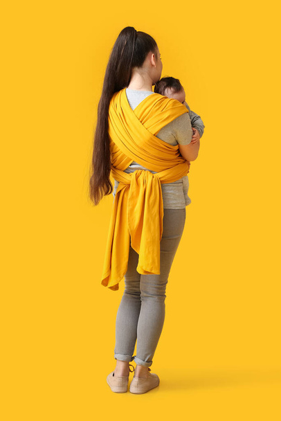 Young mother with little baby in sling on color background - Foto, Bild