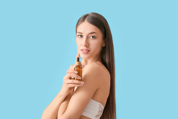 Beautiful young woman with cosmetic product on color background - Φωτογραφία, εικόνα