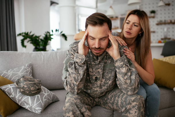 Przygnębiony żołnierz siedzący na kanapie z żoną. Młody marynarz z PTSD. - Zdjęcie, obraz