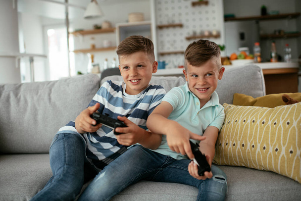 Молодые братья развлекаются, играя в видеоигры в гостиной - Фото, изображение
