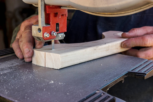 Az ácsműhelyben dolgozó közeli munkások szalagfűrésszel vágják fel a farönköt a deszkákra. Nyers fa és fából készült kézművesség. - Fotó, kép