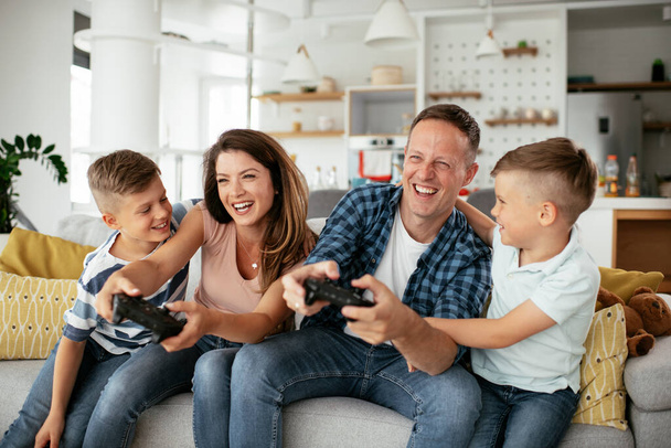  Happy loving couple are playing video games with kids at home. - Zdjęcie, obraz