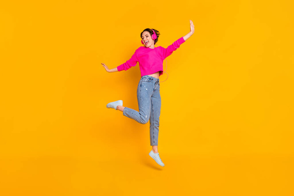 Full size photo of pretty funky lady jump high have fun listen earphones wear pullover isolated yellow color background - Φωτογραφία, εικόνα