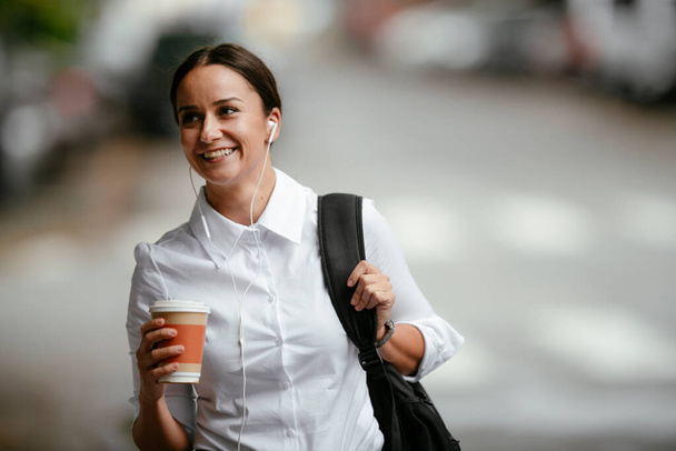 Επιτυχημένη νεαρή επιχειρηματίας ή επιχειρηματίας στο φρένο του καφέ, ενώ το περπάτημα εξωτερική.  - Φωτογραφία, εικόνα