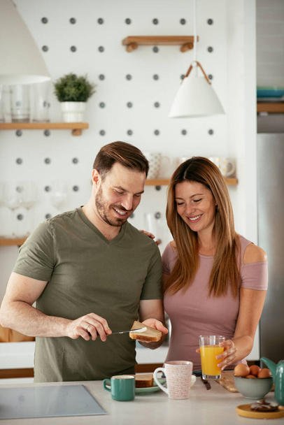 Молодая пара делает бутерброды дома. Любимая пара наслаждается на кухне. - Фото, изображение