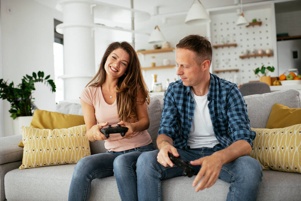 Husband and wife have a fun while playing video games at home. - Zdjęcie, obraz