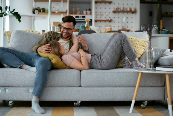 Чоловік і дружина насолоджуються диваном. Щаслива пара розслабляється у вітальні
. - Фото, зображення