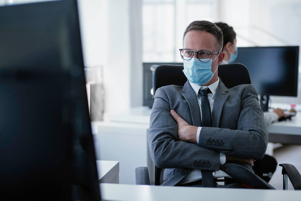 Handsome businessman with medical mask. Young businessman working in office. - Фото, зображення