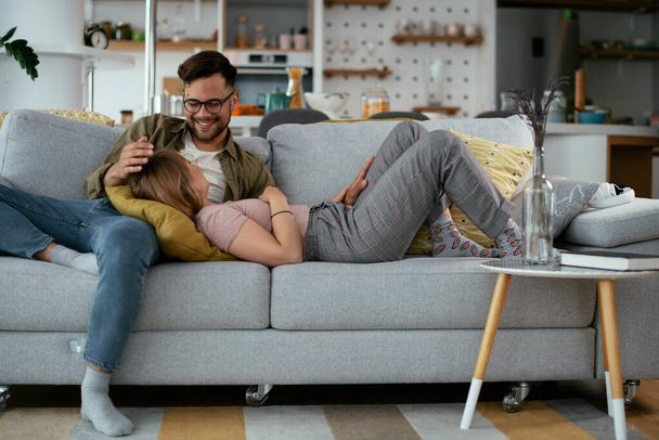 Husband and wife enjoying on sofa. Happy couple relaxing in living room. - Фото, зображення