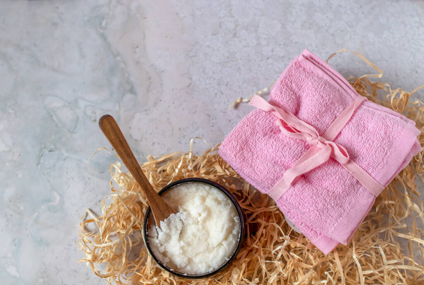 A jar of white sugar scrub with a wooden spoon, next to some bright pink cloths. Natural cosmetics or home spa concept. - Foto, afbeelding