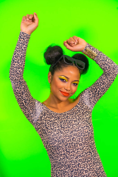 A closeup of a young fashion girl with bright makeup and two tails hairstyle wearing a leopard print dress with open shoulders dancing with pleasure - Foto, immagini