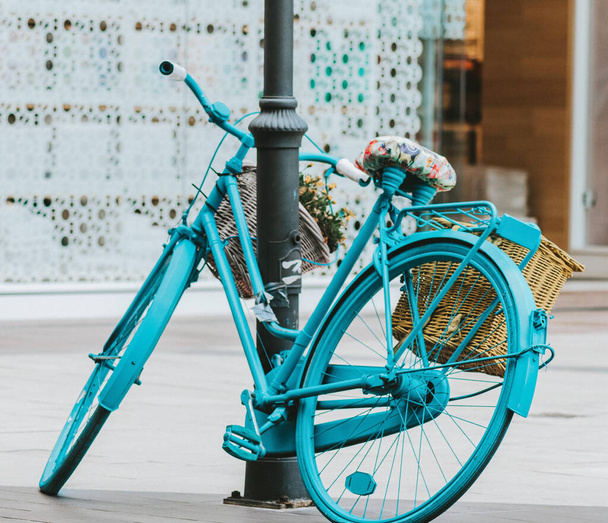 A classic blue bicycle leaning against a posy - Photo, Image