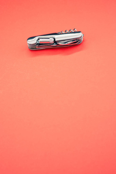 A vertical isolated shot of the multifunctional pocket knives on a pink background - Fotografie, Obrázek