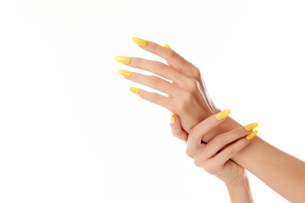 A closeup shot of a female's hands with yellow nail polish on a white background - Фото, изображение