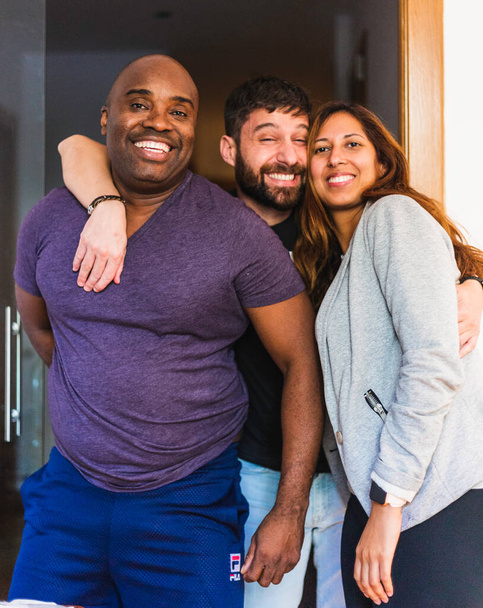 Τρεις διαφυλετικοί φίλοι, όπου μπορούμε να δούμε έναν μαύρο, έναν Ισπανό και μια Λατίνα, όλοι ποζάρουν για μια φωτογραφία. Είναι όλοι χαρούμενοι. - Φωτογραφία, εικόνα