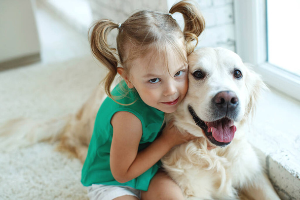 Gelukkig kind met een hond. Portret van een meisje met een huisdier. Labrador Retriever thuis.  - Foto, afbeelding
