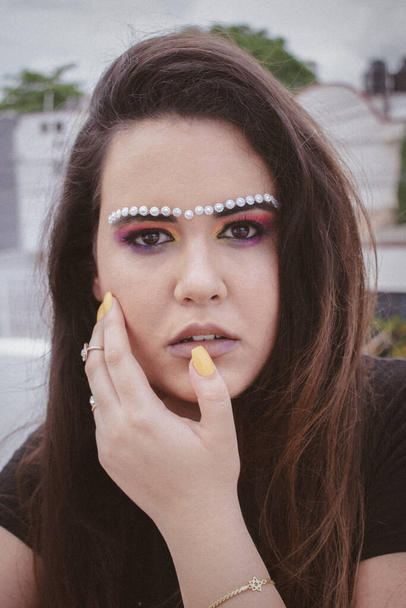 A portrait of an attractive brunette woman in creative makeup with rhinestones on her eyebrows - Foto, immagini