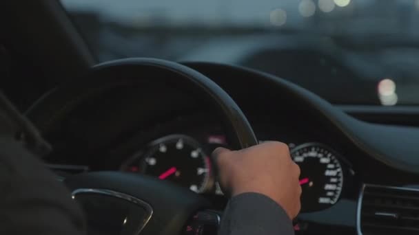 Close-up footage of unrecognizable male hands holding steering wheel of expensive auto driving in evening - Footage, Video