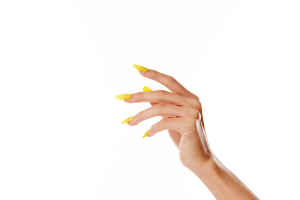 A closeup shot of a female's hand with yellow nail polish on a white background - Valokuva, kuva