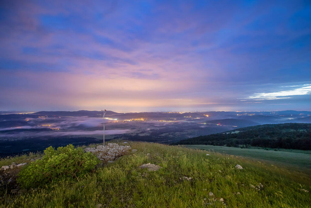Avond panorama vanaf de heuvel van Vremscica, Slovenië, op zoek naar Koper en Trieste in rijke kleuren van de nacht. Licht en wolken op de achtergrond en gras op de voorgrond. - Foto, afbeelding