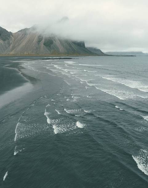 A vertical shot of a mesmerizing seascape surrounded by foggy cliffs - Foto, afbeelding