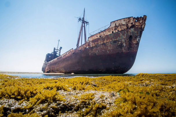 Dimitrios shipwreck in  Gythio, Greece. A partially sunk rusty metal shipwreck decaying through time on a sandy beach on a sunny day. Famous shipwreck in greece. - Photo, Image
