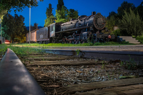 Starý parní vlak v noci zaparkovaný jako venkovní výstava železnic v parku v řeckém městě Kalamata. Parní lokomotiva s kočáry v parku na ostrově Pelenese - Fotografie, Obrázek