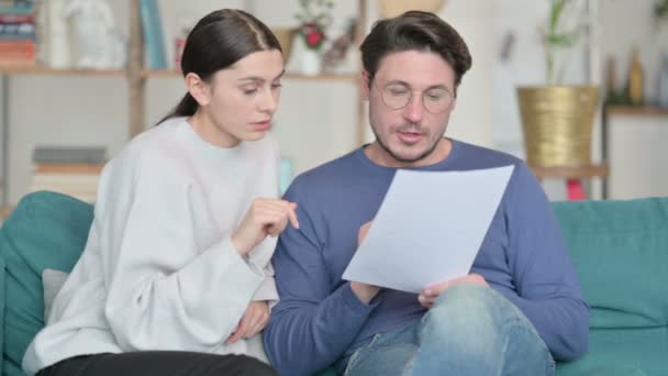 若いラテン語のカップルはソファで一緒に文書を読む  - 映像、動画