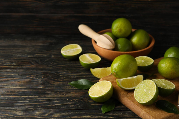 Bowl and board with lime on wooden background, space for text - Foto, Imagen