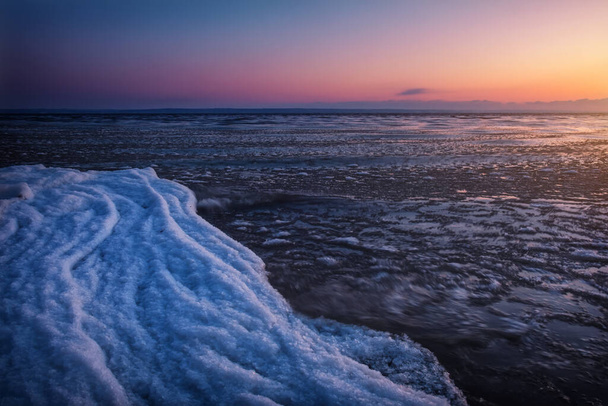 Természetes Téli táj a tengerparton naplementekor. Jég és naplemente ég.  - Fotó, kép