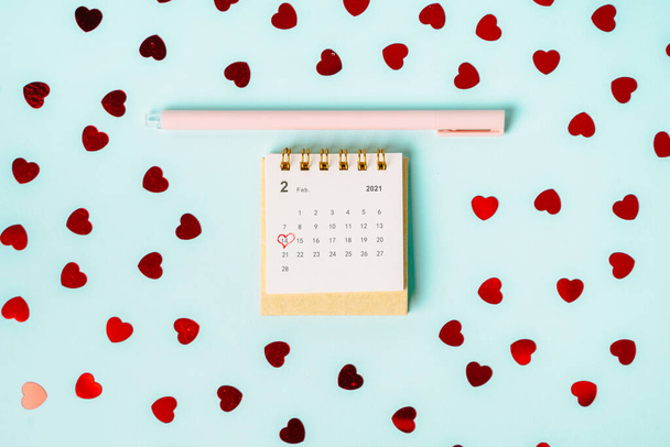 Calendario con el marcado día 14 de febrero sobre un fondo azul entre los corazones. El concepto de celebrar el Día de San Valentín - Foto, Imagen