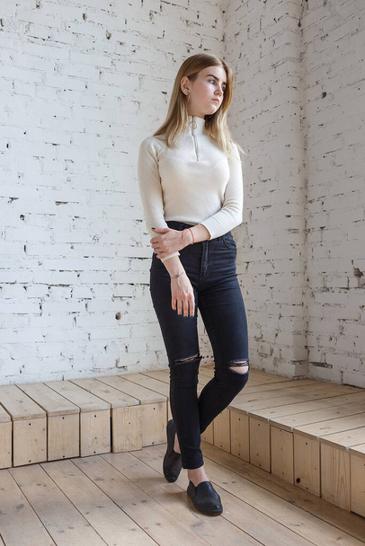 портрет молодої вдумливої підліткової моделі в білому светрі і чорних джинсах
 - Фото, зображення