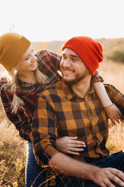 Iloinen kaveri ja tyttö kävelyllä kirkkaissa neulotuissa hatuissa ja ruudullisissa paidoissa - Valokuva, kuva