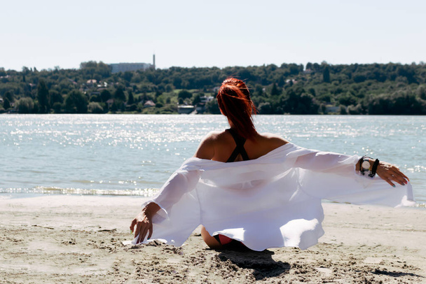 Vista posterior de la mujer despreocupada con los brazos extendidos relajándose en la playa en el día de verano.  - Foto, Imagen