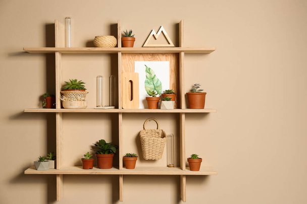 Wooden shelves with different decorative elements on beige wall, space for text - Zdjęcie, obraz