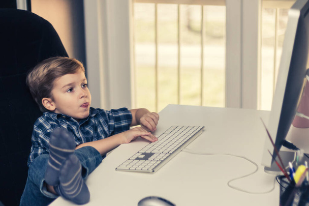 Μικρό αγόρι που παίζει παιχνίδια σε έναν υπολογιστή στο σπίτι.  - Φωτογραφία, εικόνα