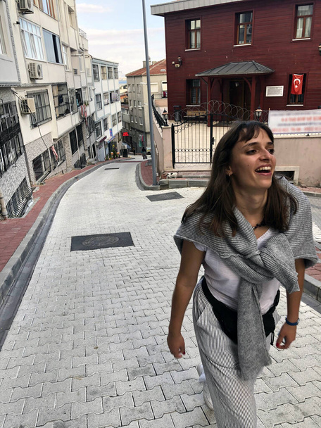 Travel woman lifestyle. Happy woman smile in Istanbul street. Young tourist in Turkish street. Style girl visit interesting place during vacation. Fashion student explore historic trip - Zdjęcie, obraz