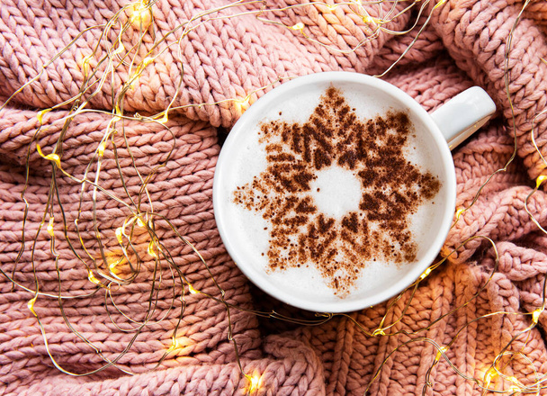 Café con un patrón de copo de nieve sobre un fondo de jersey de punto cálido. Vista superior - Foto, Imagen