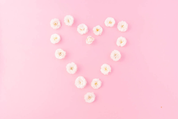 Flowers composition. heart frame of white small rose on pink background. Mother's day, Valentine's day, birthday, spring, summer concept. Flat lay, top view, copy space - Fotoğraf, Görsel