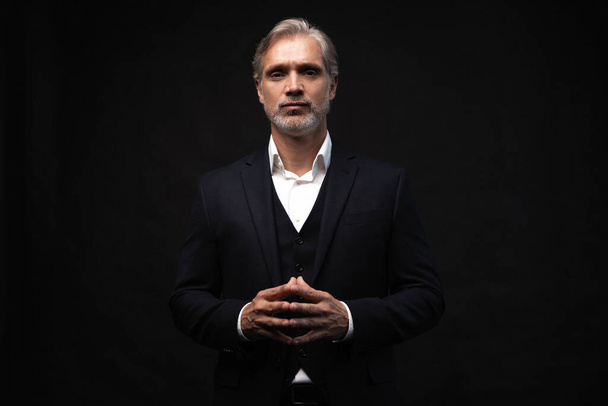 Handsome middle-aged man in suit posing against black background - Photo, Image
