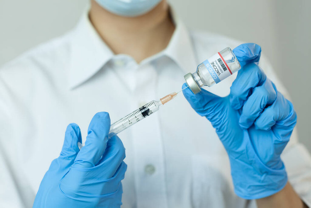 Taking COVID-19 vaccine into syringe. Doctors create invent coronavirus vaccine. Hand hold ampoule, medicine for pandemic applied. Starting of people vaccination, epidemic finishes. - Foto, Imagen