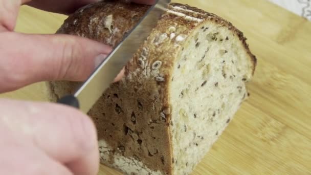 Lähikuva kuvamateriaalia mies käsi leikkaamalla leipää puinen leikkuulauta - Materiaali, video