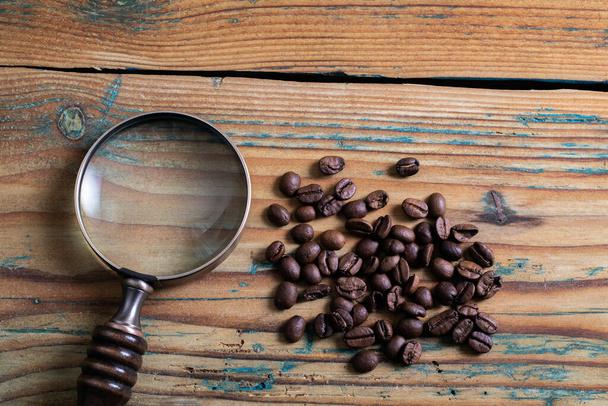 Des grains de café et une loupe sur une table en bois. Recherche et concept de recherche - Photo, image